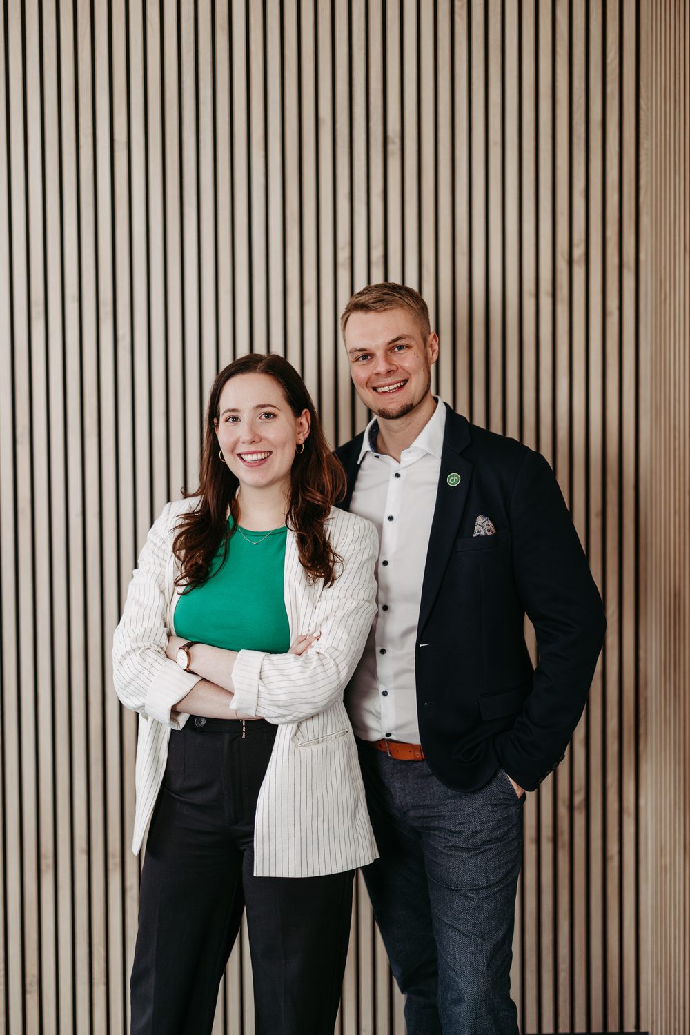 Verena und Jan Heiss stehen lächelnd vor einer Holzwand