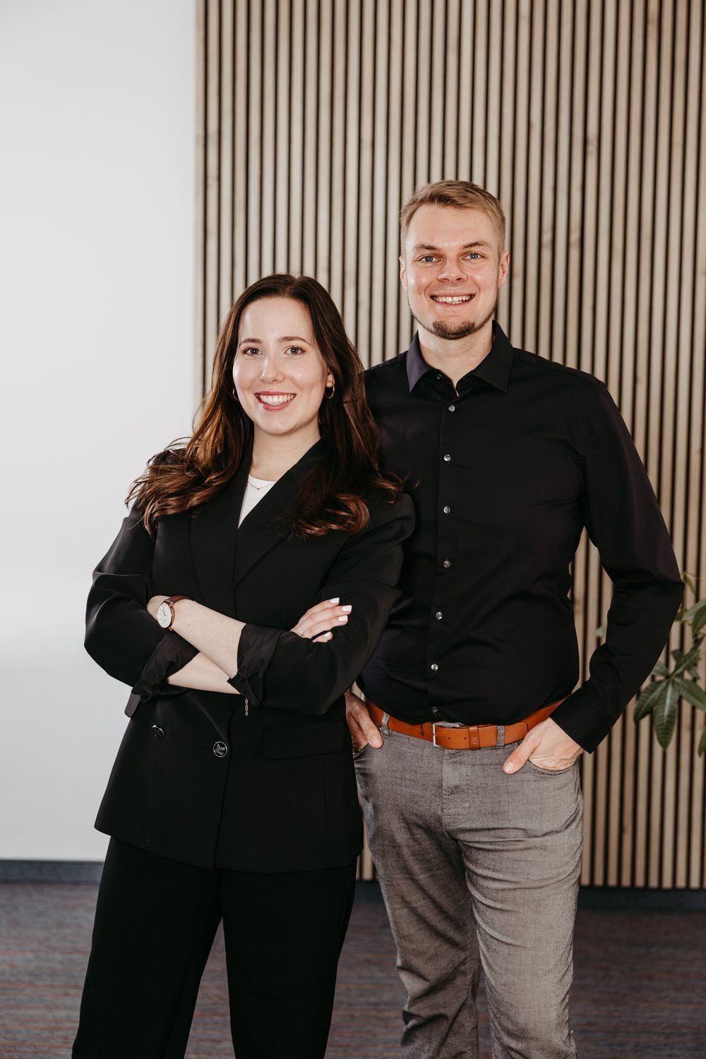Verena und Jan Heiss stehen lächelnd nebeneinander vor einer Holzwand